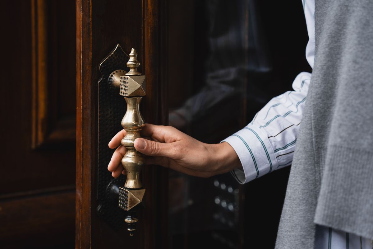 A hand turning a brass door handle